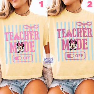 May include: A light yellow t-shirt with the text "TEACHER MODE OFF" in pink, with a Minnie Mouse graphic and a castle silhouette. The design includes light blue vertical stripes and a pink bow.