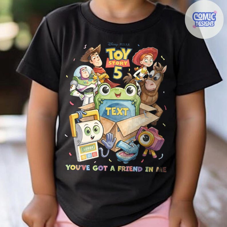 May include: A black short-sleeved t-shirt featuring a Toy Story 5 graphic with characters including Woody, Buzz Lightyear, Jessie, and Bullseye. A green frog sits in a cardboard box with the word TEXT, and the phrase YOU'VE GOT A FRIEND IN ME.