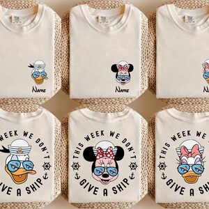 May include: Six cream-colored t-shirts, each folded and arranged on a woven mat. The shirts feature cartoon characters like Donald Duck, Minnie Mouse, and Daisy Duck, wearing sunglasses. Some shirts have the text "This Week We Don't Give a Ship."
