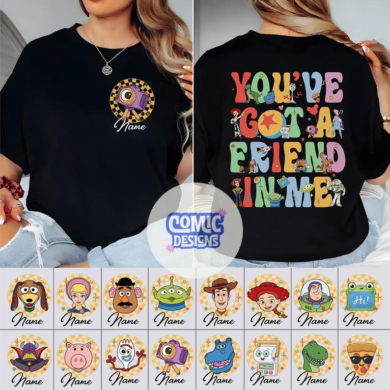 Op de afbeelding: Een zwart t-shirt met een kleine ronde afbeelding op de voorkant met een camera en het woord Name. De achterkant toont de tekst You've Got A Friend In Me in kleurrijke letters, omringd door diverse illustraties van stripfiguren.