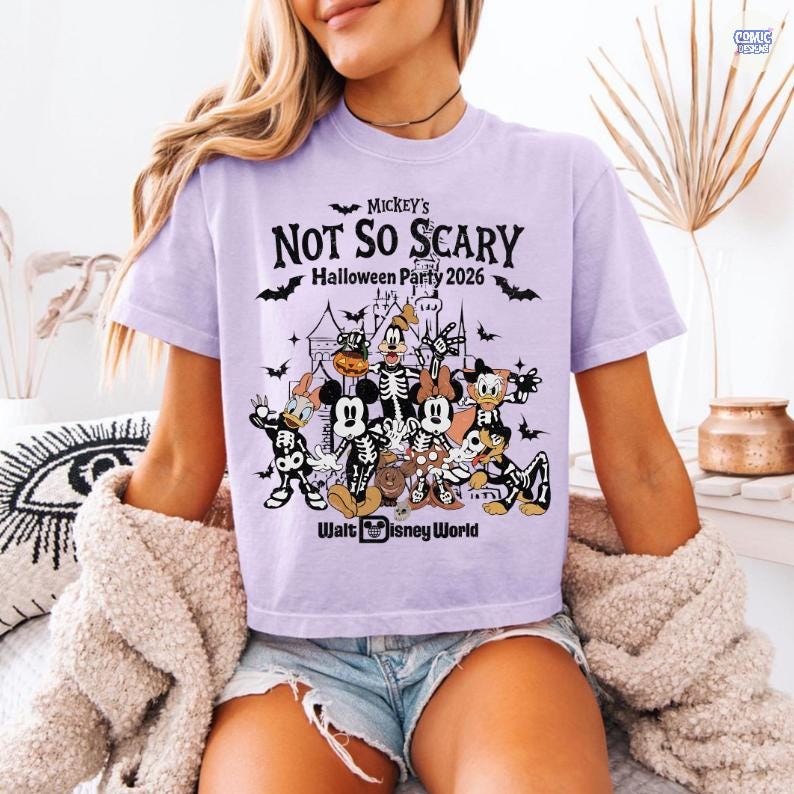 May include: A light purple t-shirt featuring a graphic for Mickey's Not So Scary Halloween Party 2026 at Walt Disney World. The graphic includes various Disney characters in Halloween costumes, bats, and a haunted house.