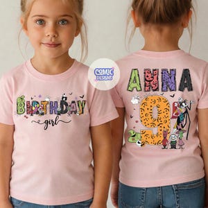 May include: A light pink t-shirt featuring the text "BIRTHDAY girl" on the front and the name "ANNA" with the number "9" on the back. The designs include colorful, patterned letters and various animated character illustrations from a movie.