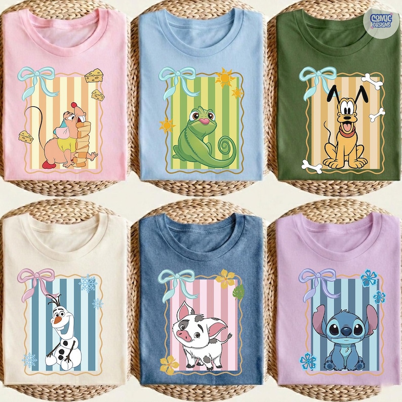 May include: Six colorful t-shirts with cartoon character designs. The shirts are pink, light blue, olive green, off-white, navy blue, and lavender. Each shirt features a different character within a decorative frame with a bow.