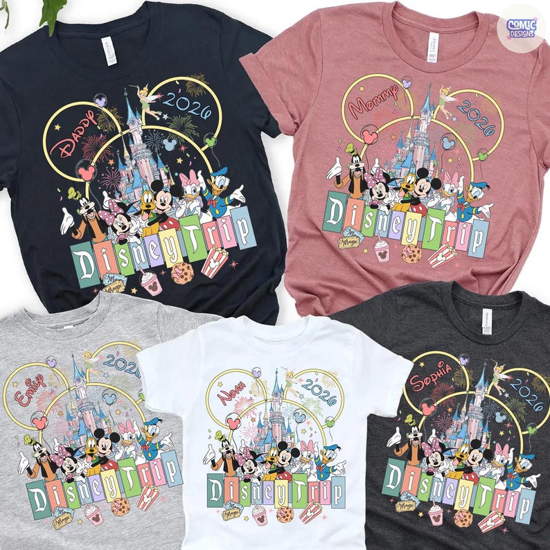 May include: Assorted-color Disney Trip t-shirts featuring Mickey Mouse, Minnie Mouse, Donald Duck, and other characters. Each shirt has a different name and the year 2026 or 2020. The shirts are in various colors, including navy, pink, gray, white, and charcoal.