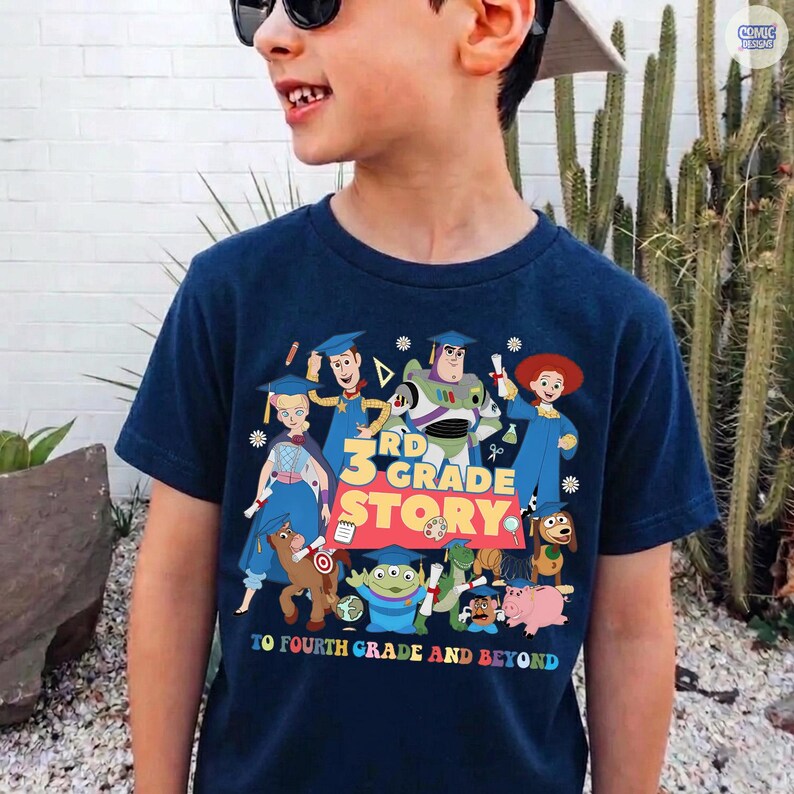 May include: Navy blue t-shirt featuring a colorful graphic of Toy Story characters wearing graduation caps. The text reads "3rd Grade Story" and "To Fourth Grade and Beyond".