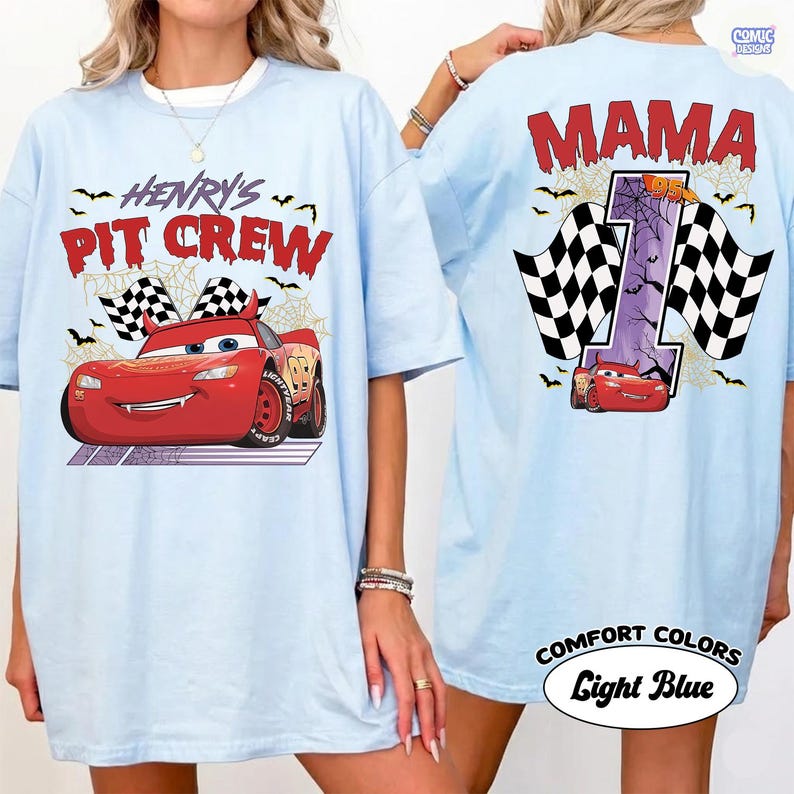 Puede incluir: Una camiseta azul claro con un gr&aacute;fico de coche de carreras rojo en la parte delantera con el texto "HENRY'S PIT CREW" y banderas a cuadros. La parte trasera muestra el texto "MAMA" sobre un n&uacute;mero "1" grande con telara&ntilde;as y un coche rojo.