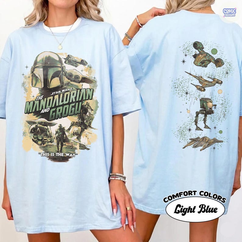 Op de afbeelding: Lichtblauw T-shirt met afbeeldingen uit de Star Wars-serie "The Mandalorian and Grogu". De voorkant toont de Mandalorian en Grogu, met de tekst "This is the Way". De achterkant toont verschillende ruimteschepen en personages.