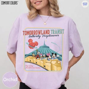 Puede incluir: Camiseta Comfort Colors color orqu&iacute;dea con un gr&aacute;fico de Tomorrowland Transit Authority Peoplemover. El dise&ntilde;o incluye a Mickey Mouse, Minnie Mouse, Goofy y otros personajes de Disney en un tren amarillo. La camiseta tiene el texto "Keep moving forward to a new tomorrow."