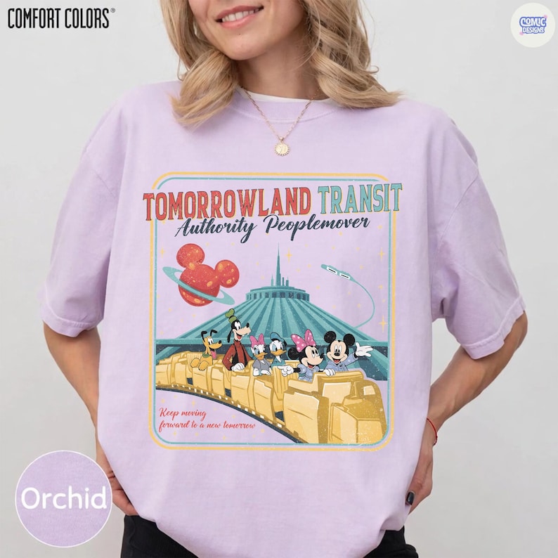 Puede incluir: Camiseta Comfort Colors color orqu&iacute;dea con un gr&aacute;fico de Tomorrowland Transit Authority Peoplemover. El dise&ntilde;o incluye a Mickey Mouse, Minnie Mouse, Goofy y otros personajes de Disney en un tren amarillo. La camiseta tiene el texto "Keep moving forward to a new tomorrow."