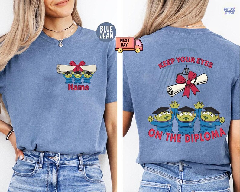 May include: Blue short-sleeved t-shirt with a graduation-themed graphic. The front features three green aliens holding a diploma with a red bow, with the text "Name" below. The back says "Keep Your Eyes On The Diploma".