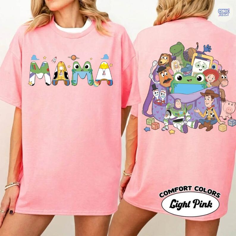 May include: A light pink t-shirt featuring the word MAMA on the front, with letters styled after various characters. The back displays a graphic of a purple backpack filled with multiple animated characters, including a space ranger and a cowboy.