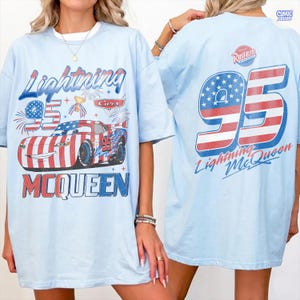 Puede incluir: Camiseta azul claro con un dise&ntilde;o de Rayo McQueen de la pel&iacute;cula Cars. El dise&ntilde;o frontal incluye "Lightning 95 McQueen" con un dise&ntilde;o de coche patri&oacute;tico. La parte trasera muestra "95" con una bandera americana y "Lightning McQueen".