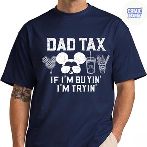 May include: Navy blue t-shirt with the text "DAD TAX" above a Mickey Mouse head wearing sunglasses, a popsicle, a drink, and a dessert. The text "IF I'M BUYIN' I'M TRYIN'" is below the graphic. The shirt has short sleeves.