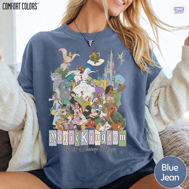 Puede incluir: Camiseta azul vaquero Comfort Colors con un gr&aacute;fico colorido de personajes de Disney. El dise&ntilde;o incluye a Mickey Mouse, Peter Pan y el castillo de Cenicienta. El texto "Magic Kingdom Walt Disney World" tambi&eacute;n est&aacute; impreso en la camiseta.