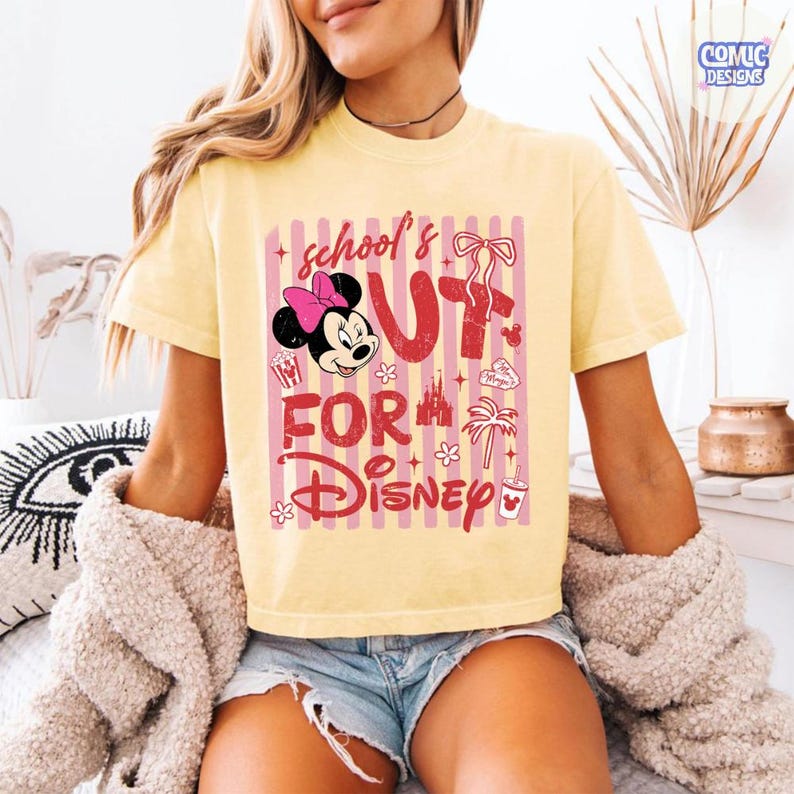 May include: A yellow t-shirt with a pink and white striped design. The shirt features Minnie Mouse with a pink bow and the text "school's out for Disney" in red. Additional graphics include a bow, palm tree, and popcorn.