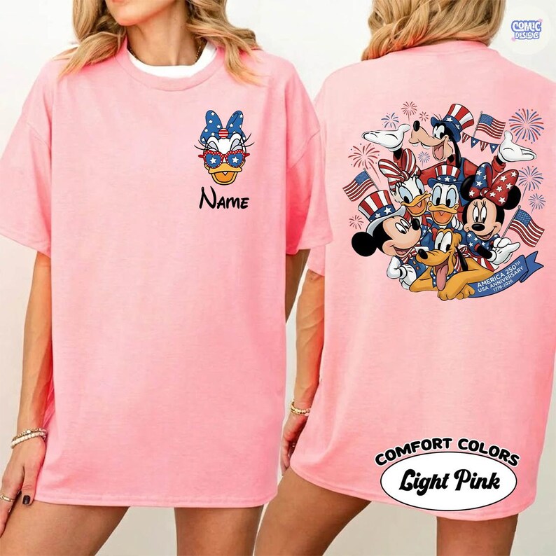 May include: Light pink t-shirt featuring Daisy Duck wearing sunglasses and a patriotic bow. The front of the shirt has the word "Name" below the graphic. The back of the shirt features Mickey, Minnie, Donald, Goofy, and Pluto with American flags.