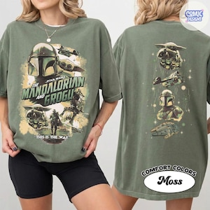 Puede incluir: Camiseta verde oliva con un dise&ntilde;o de Star Wars de The Mandalorian y Grogu. La parte delantera muestra el texto "The Mandalorian and Grogu" y "This is the Way". La parte trasera tiene ilustraciones de personajes y naves.