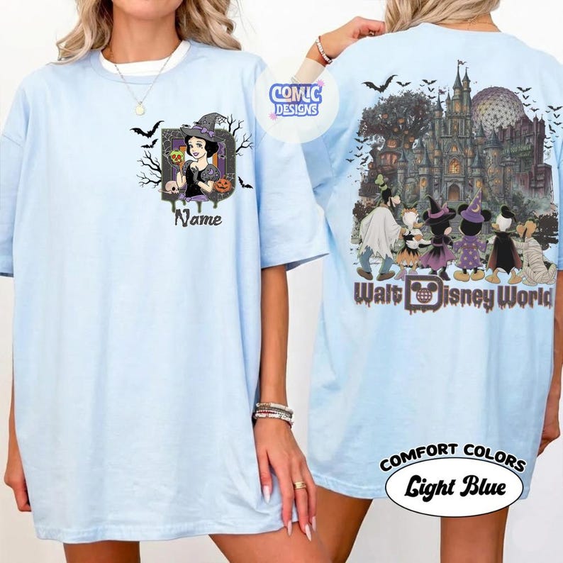 May include: A light blue t-shirt featuring a front graphic of a character in a witch hat with the text Name and a back graphic of cartoon characters in Halloween costumes standing before a castle with the text Walt Disney World.