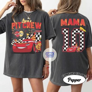 May include: Dark gray t-shirt featuring a red race car graphic with the text "Luca's PIT CREW" on the front. The back of the shirt displays "MAMA" above a checkered number 10 and a smaller car graphic. The shirt is labeled "Comfort Colors Pepper".