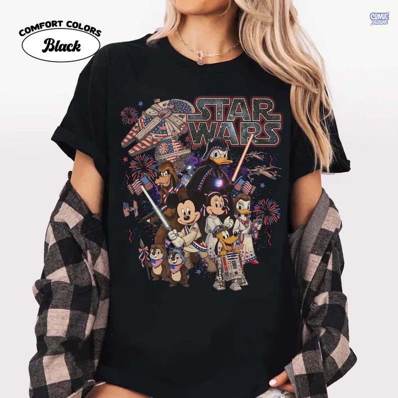 May include: Black t-shirt featuring a Star Wars graphic with Disney characters, fireworks, and an American flag theme. The shirt includes the text "STAR WARS" and "COMFORT COLORS Black".