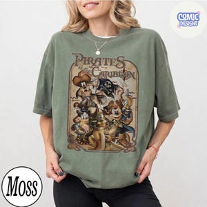 May include: A moss green t-shirt featuring a vintage-style graphic of Disney characters in pirate attire, with the text "Pirates of the Caribbean" in a distressed font. The shirt has short sleeves and a relaxed fit.