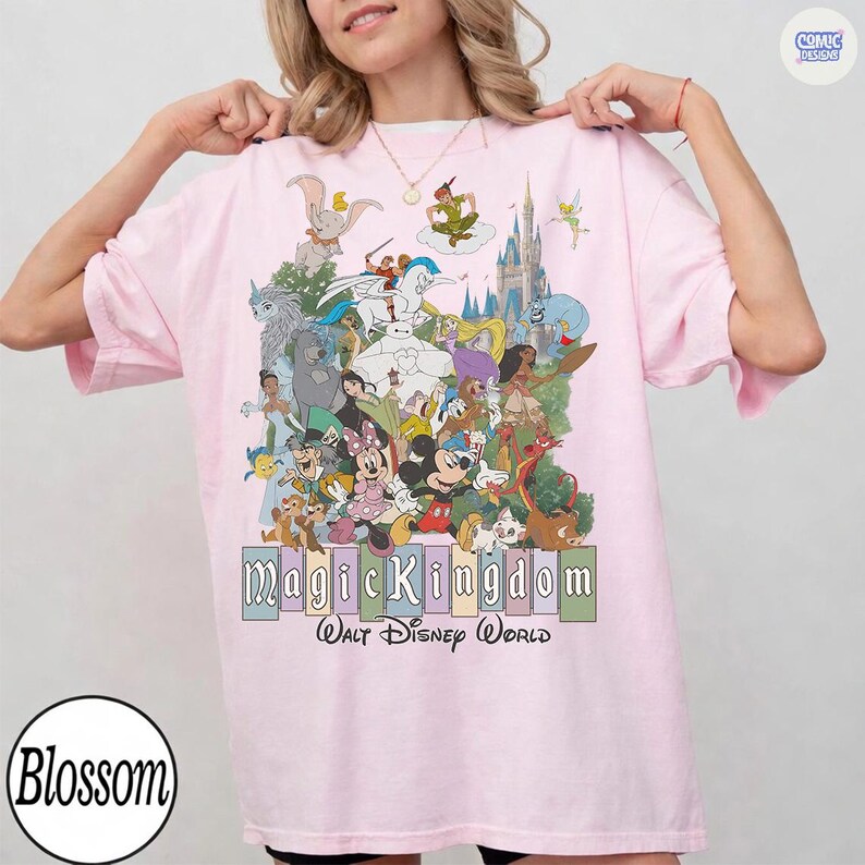 Puede incluir: Camiseta rosa claro con un dise&ntilde;o colorido de personajes de Disney, incluyendo a Mickey y Minnie Mouse, y Peter Pan. El texto "Magic Kingdom Walt Disney World" se muestra debajo. La camiseta tiene mangas cortas.
