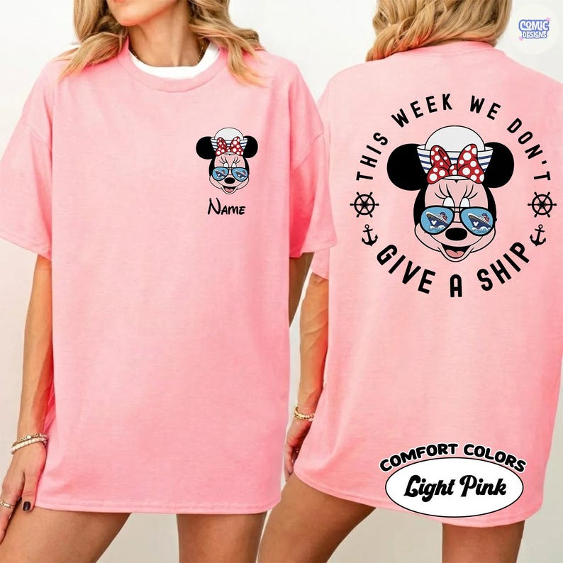 May include: Light pink t-shirt featuring a Minnie Mouse graphic on the front and back. The front has a Minnie Mouse face with sunglasses and the word "Name". The back says "This week we don't give a ship" with Minnie Mouse and nautical elements.