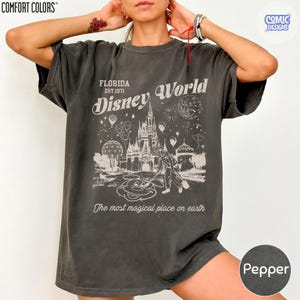 K&ouml;nnte beinhalten: Dunkelgraues T-Shirt mit einem Vintage-Design von "Disney World". Das Design zeigt ein Schloss, Mickey Mouse und den Text "Florida Est. 1971" und "The most magical place on earth."