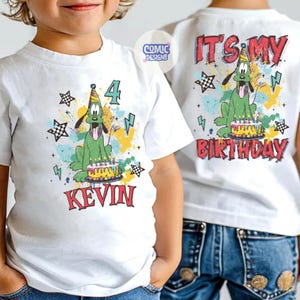 Puede incluir: Camiseta blanca con un perro de dibujos animados verde con un gorro de fiesta y una tarta de cumplea&ntilde;os. El n&uacute;mero "4" y el nombre "KEVIN" est&aacute;n impresos en la parte delantera. La parte trasera dice "IT'S MY BIRTHDAY".