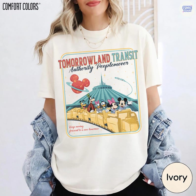 Puede incluir: Camiseta color marfil con un dise&ntilde;o gr&aacute;fico retro de la atracci&oacute;n Tomorrowland Transit Authority Peoplemover, con Mickey Mouse y sus amigos. El dise&ntilde;o incluye el texto "Tomorrowland Transit Authority Peoplemover" y "Keep moving forward to a new tomorrow."