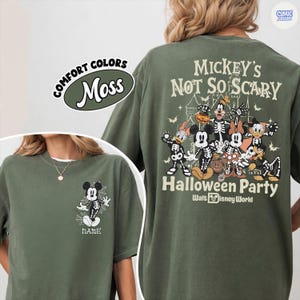 Puede incluir: Camiseta verde musgo con dise&ntilde;o de Halloween. La parte delantera muestra a Mickey Mouse esqueleto con una telara&ntilde;a, y la trasera presenta a Mickey y sus amigos con disfraces de esqueleto con el texto "Mickey's Not So Scary Halloween Party" y "Walt Disney World".