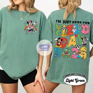K&ouml;nnte beinhalten: Hellgr&uuml;nes T-Shirt mit einem Minnie Mouse-Motiv auf einem Regenbogen und dem Text "Your Name". Auf der R&uuml;ckseite steht "I'M JUST HERE FOR FIELD DAY 2023" mit Zeichentrickfiguren. Das T-Shirt ist hellgr&uuml;n.