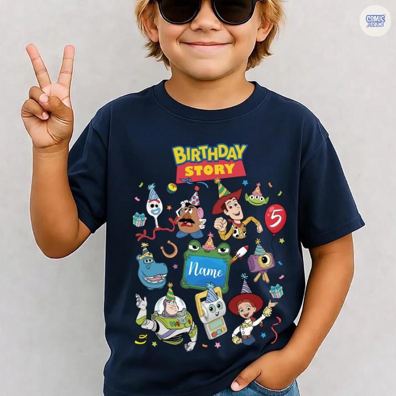 May include: A navy blue short-sleeve t-shirt featuring a colorful graphic print with the text "BIRTHDAY STORY" and "Name". The design includes various animated characters wearing party hats, confetti, and a red balloon with the number 5.