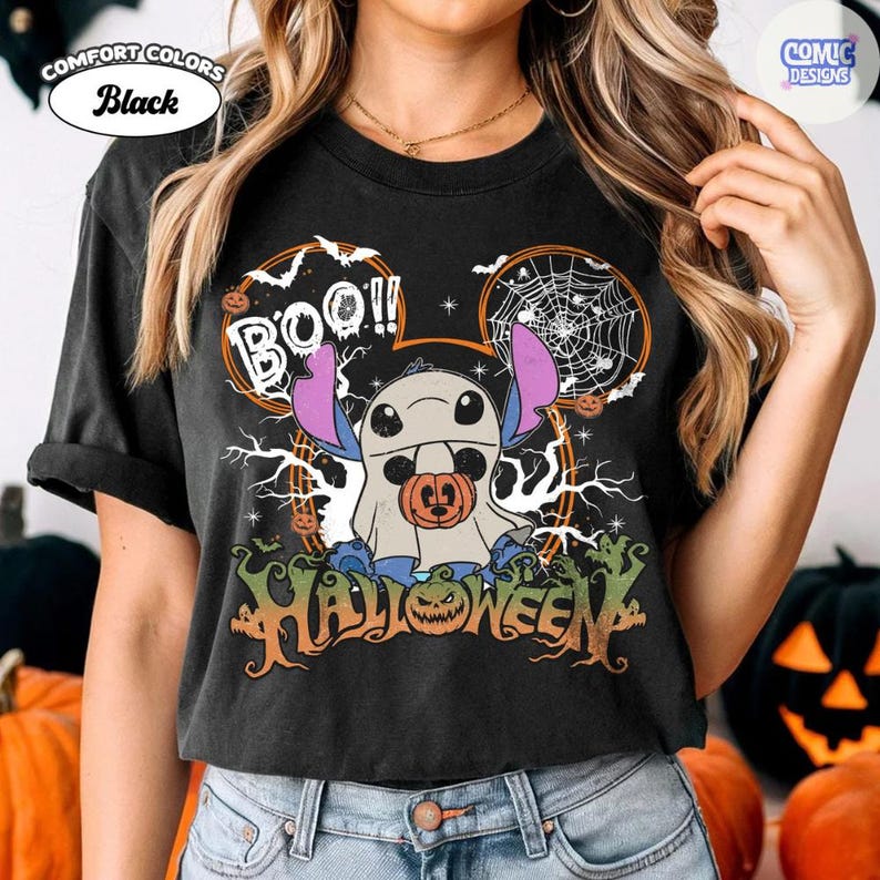 Peut inclure: Un t-shirt noir avec un motif repr&eacute;sentant un personnage d&eacute;guis&eacute; en fant&ocirc;me tenant une citrouille. Le design inclut le texte "BOO!!" et "HALLOWEEN" avec des accents orange et blancs, des toiles d'araign&eacute;e, des chauves-souris et des arbres.