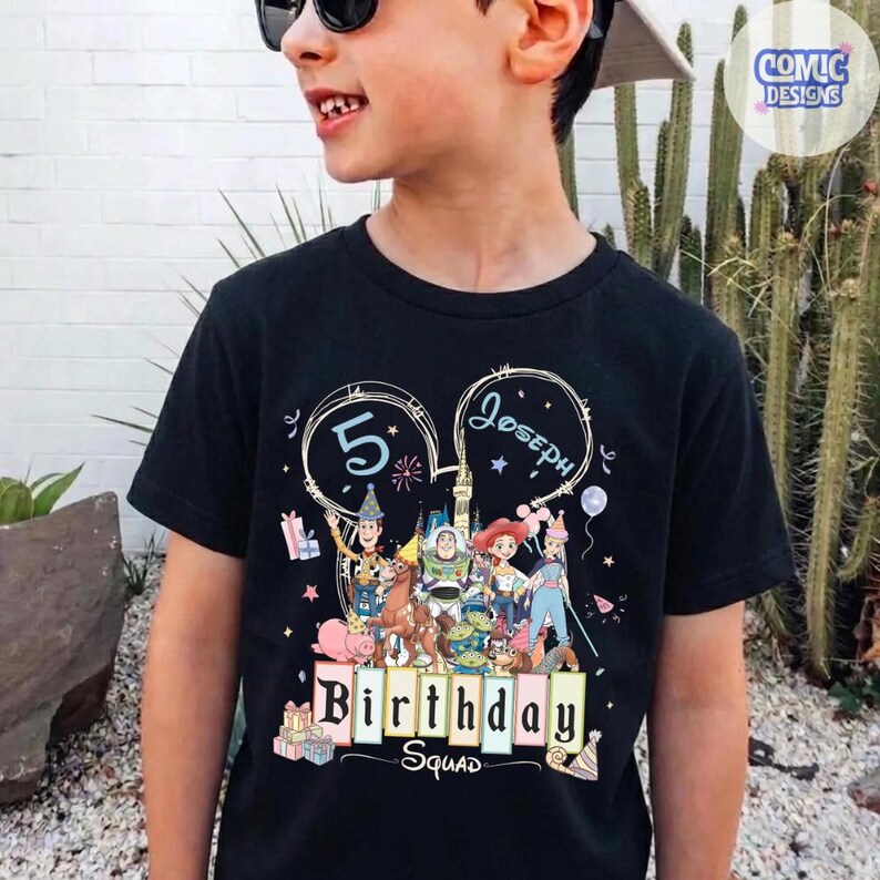 May include: Black t-shirt featuring a colorful graphic of cartoon characters and the text "Birthday Squad". The design includes the number "5" and the name "Joseph". The shirt has a crew neck and short sleeves.
