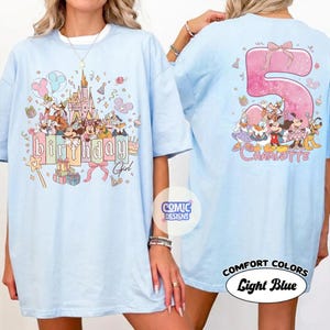May include: Light blue t-shirt featuring a colorful graphic of Disney characters, a castle, and the words "birthday girl." The back of the shirt displays a large pink number 5 with a bow, Disney characters, and the name "Charlotte."