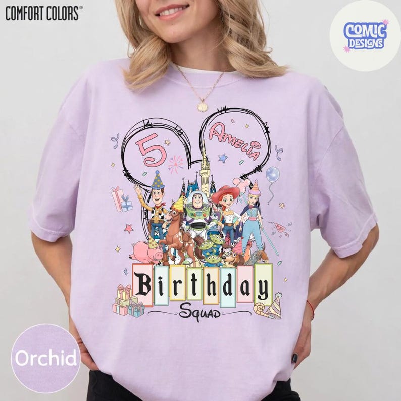May include: Orchid-colored t-shirt with a graphic featuring Disney characters, the number 5, and the name "Amelia" in a Mickey Mouse ear design. The text "Birthday Squad" is also displayed. The shirt is from Comfort Colors.