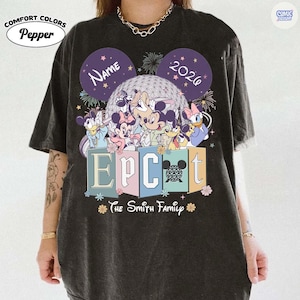 May include: Dark gray t-shirt featuring a colorful graphic of Disney characters in front of a geodesic sphere. The word "EPCOT" is displayed in pastel colors, with "The Smith Family" below. The shirt includes the text "Name" and "2026" in Mickey Mouse ear shapes.