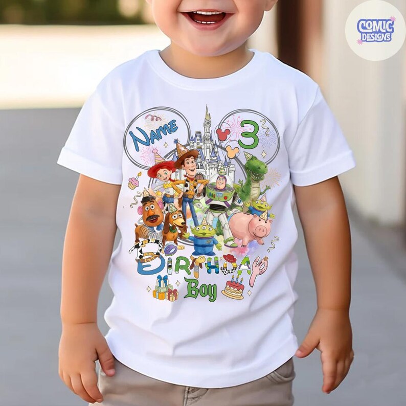 以下が含まれることがあります： 白いTシャツ。トイ・ストーリーのキャラクター、お城、そして「Name」と「3」の文字が描かれたカラフルなグラフィック。Tシャツには「Birthday Boy」の文字と、プレゼントとケーキの画像も含まれています。