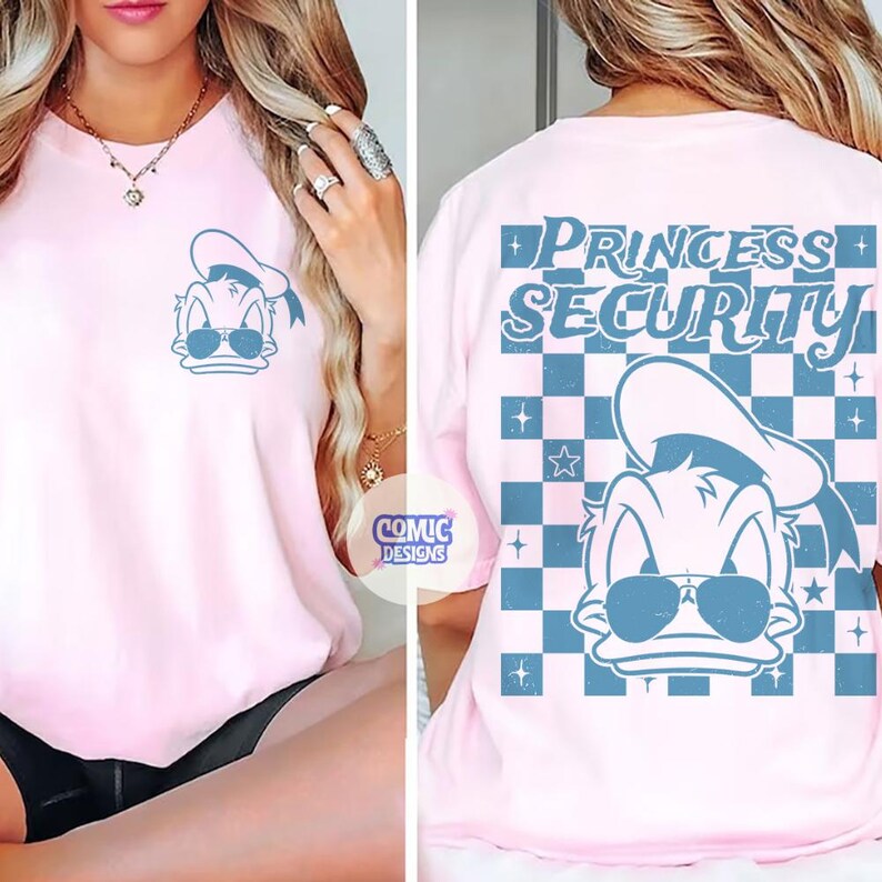 May include: Pink t-shirt featuring a cartoon duck wearing sunglasses and a sailor hat. The front of the shirt has a small graphic of the duck, while the back displays the words "PRINCESS SECURITY" in blue, set against a checkered pattern.