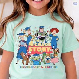 May include: A light green t-shirt featuring a colorful graphic of characters from a popular animated movie, with the text "4th Grade Story" and "To Fifth Grade and Beyond". The design includes various cartoon figures.