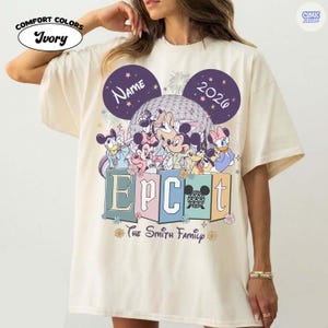 May include: Ivory-colored Comfort Colors t-shirt featuring a Disney-themed graphic. The design includes Mickey Mouse, Minnie Mouse, Donald Duck, and other characters, with the text "EPCOT" and "The Smith Family". The shirt also has the year "2026" and space for a name.