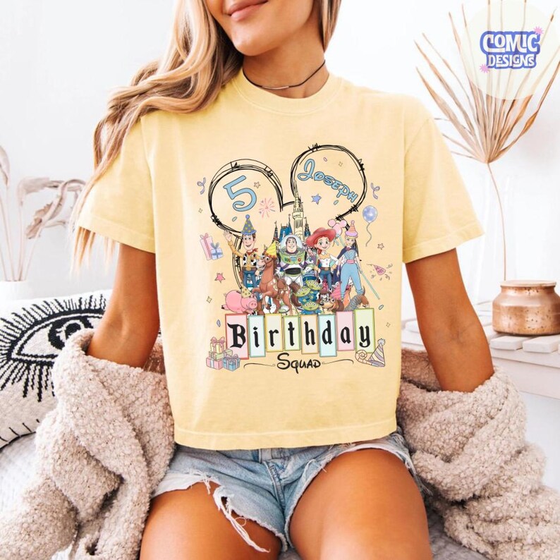 May include: Yellow t-shirt with a graphic featuring Disney characters and the text "Birthday Squad". The design includes the number "5" and the name "Joseph" in a Mickey Mouse ear outline. The shirt is a light yellow color.