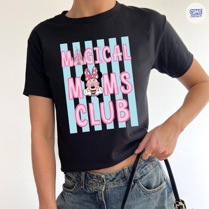 K&ouml;nnte beinhalten: Schwarzes T-Shirt mit dem Text "MAGICAL MOMS CLUB" in rosa Buchstaben, vor hellblauen vertikalen Streifen. Eine Minnie Mouse-Grafik ist unter dem Wort "MAGICAL" zentriert. Das Shirt hat kurze &Auml;rmel.