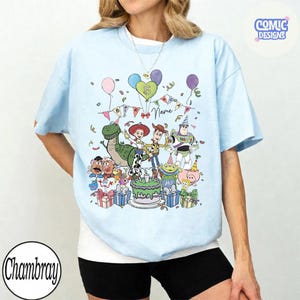 Puede incluir: Una camiseta azul claro con un gr&aacute;fico colorido de personajes de Toy Story como Woody, Buzz Lightyear, Jessie y Rex alrededor de un pastel de cumplea&ntilde;os. El dise&ntilde;o incluye globos, confeti y el texto 5 Birthday Name.