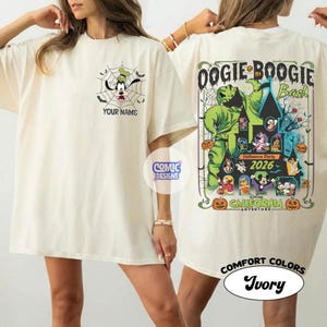 May include: Ivory-colored t-shirt featuring a cartoon of Goofy in a spiderweb with the text "YOUR NAME". The back of the shirt has a graphic for the "Oogie Boogie Bash" Halloween Party 2026 at Disney California Adventure.