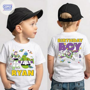 Puede incluir: Camiseta blanca con un dibujo animado de Buzz Lightyear y una nave espacial verde, con el nombre "RYAN" en amarillo. La parte trasera de la camiseta dice "BIRTHDAY BOY" con un dibujo de Buzz Lightyear volando.