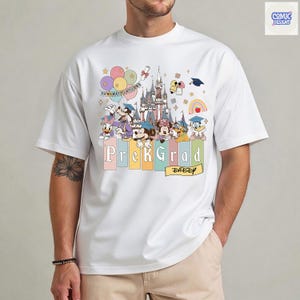 May include: White t-shirt featuring a colorful graphic of Disney characters, a castle, balloons, and the words "Prek Grad Daddy." The design includes Mickey Mouse, Minnie Mouse, Donald Duck, and other characters, with graduation-themed elements.