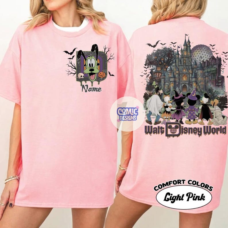May include: A light pink t-shirt featuring a front graphic of Goofy inside a letter D with bats and a skull. The back displays a haunted castle, Epcot sphere, and Disney characters in Halloween costumes with the text Walt Disney World.