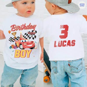 Puede incluir: Camiseta blanca con un gr&aacute;fico de coche de carreras rojo, las palabras "Birthday BOY" y un dise&ntilde;o de bandera a cuadros. La parte posterior de la camiseta tiene un gran n&uacute;mero 3 rojo y el nombre "LUCAS". El ni&ntilde;o lleva vaqueros azules y una gorra de b&eacute;isbol gris.